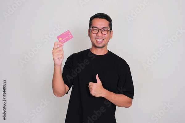 Fototapeta A man smiling happy and give thumbs up while holding credit card