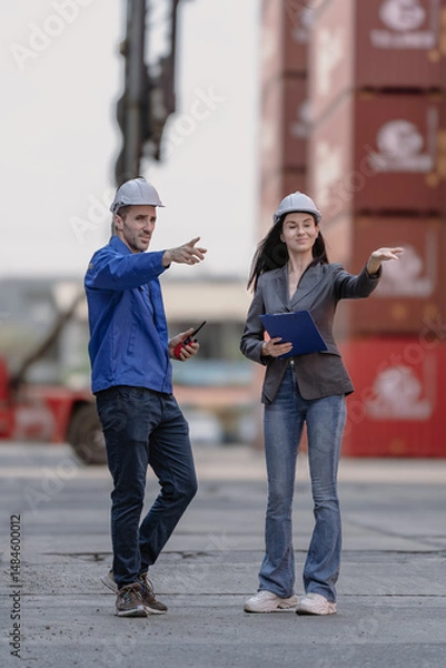 Fototapeta Industrial engineer standing at shipping container yard inspecting cargo delivering loading as plan. Woman manager and diverse ethnic worker checking import export container at logistic terminal dock.