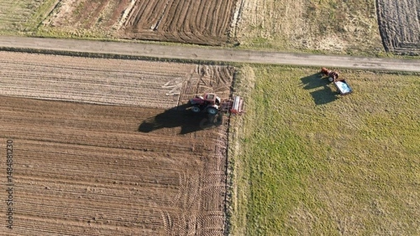 Fototapeta Farmer using machinery for field preparation