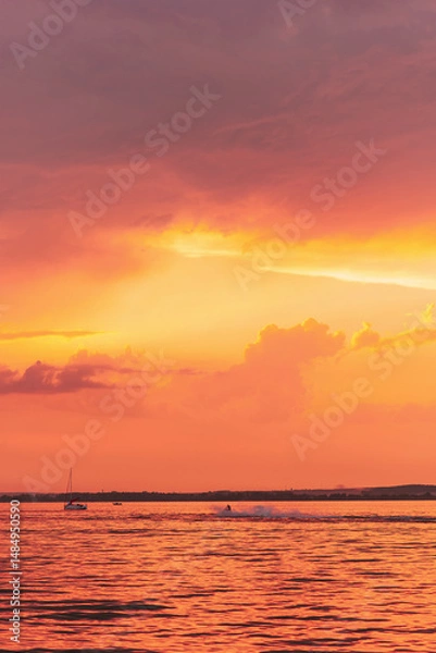 Fototapeta Boat is sailing in ocean with beautiful orange sky in the background on sunset