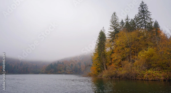 Fototapeta Plitvice Lakes in Croatia during autumn, showcasing stunning waterfalls, vibrant foliage, and crystal-clear waters, creating a magical and serene natural landscape. Lake fog with Autumn foliage