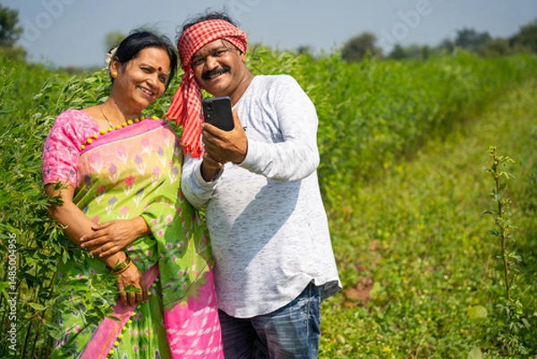 Obraz Happy Indian farmer couple at their farm using smartphone