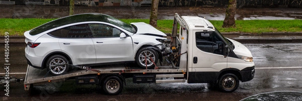 Obraz Tow truck with a broken car on road. Tow truck transporting a white car on the highway.