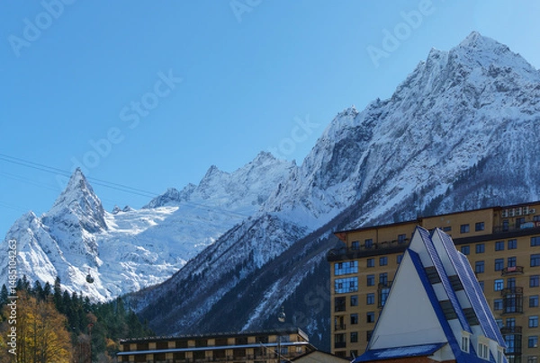 Obraz Cable car cabins in Dombay against amazing snow-capped peaks and majestic blue slopes of North Caucasus Mountains. Russia