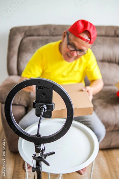 Obraz Asian Elderly Male Vlogger Doing "Unboxing" Video From Home