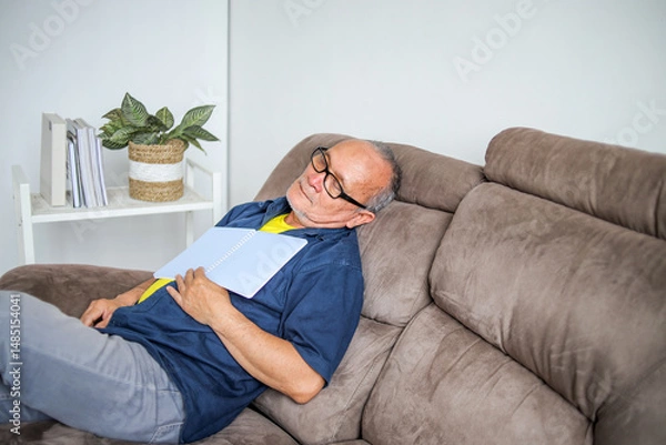 Obraz Headshot Of Asian Elderly Male Sleeping On Sofa With Book