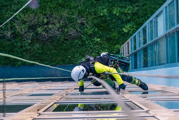 Fototapeta Rope access specialist washes the facade of a building