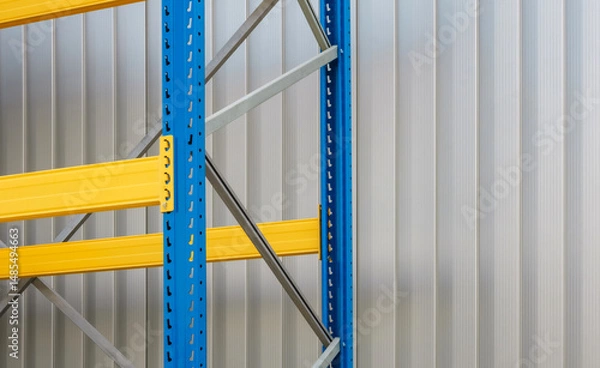 Obraz A close-up view of a sturdy industrial pallet racking system featuring against a light gray corrugated metal wall. Suitable for logistics, manufacturing,or industrial supply projects.