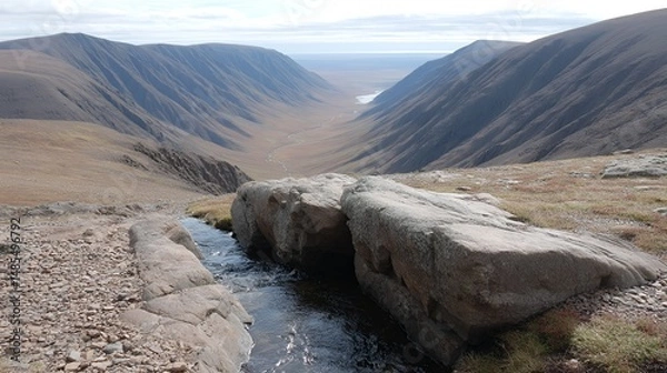 Fototapeta flowing water carving narrow paths through tundra rocks