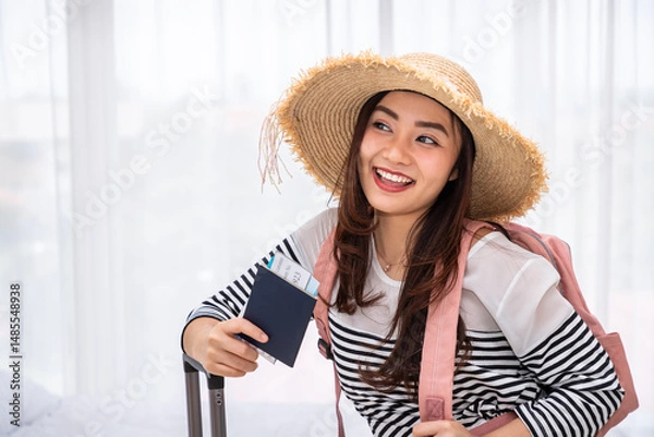Fototapeta Smiling young Asian woman traveler with passport and boarding pass ready for vacation