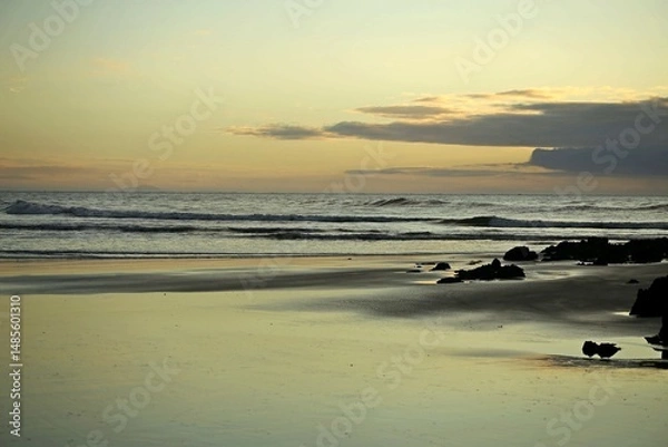 Obraz Silver light reflection over beach wet sand, yellowish light at horizon line, sunrise in Itacuruca beach, Cananeia, south Sao Paulo state 