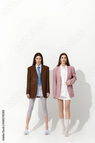 Fototapeta Stylish twin sisters showcase their unique fashion in a minimalist setting