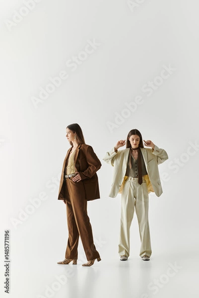 Fototapeta Stylish twin sisters showcasing their fashionable outfits in a minimalist studio setting
