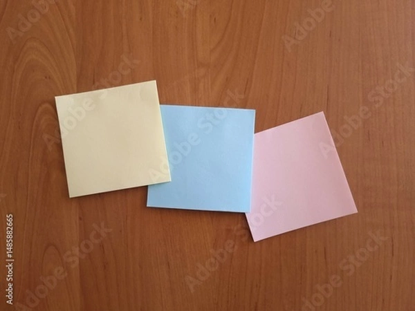 Obraz Three colored square note papers on wooden background