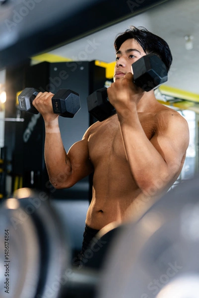 Obraz Bodybuilder lifting weights in gym showing muscular physique
