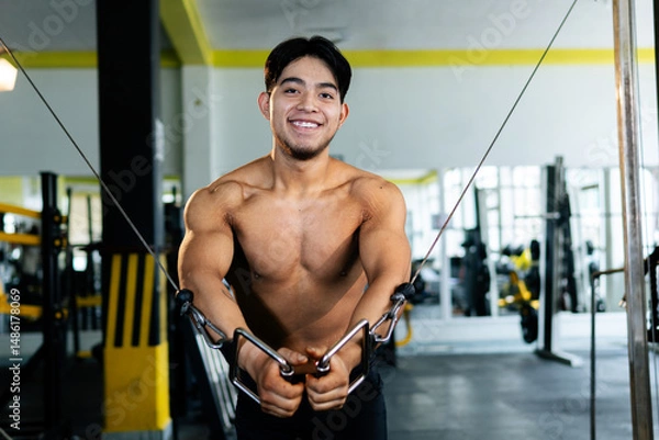 Obraz Young bodybuilder doing cable crossover exercise in gym