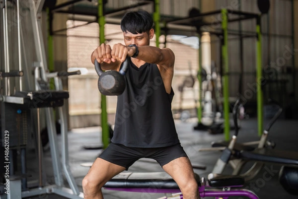 Obraz Kettlebell Workout. Man lifting kettlebell in gym for functional fitness and strength.