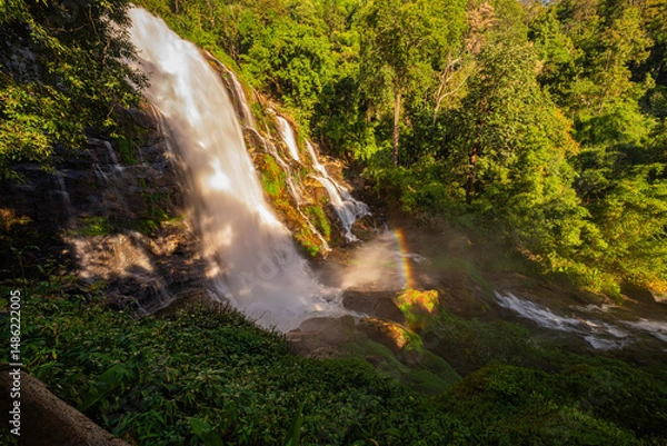 Obraz Wachirathan waterfall Chiang Mai is surrounded by lush greenery, with a vibrant rainbow forming in the mist. Water droplets hit by sunlight create rainbows that we can see all day long..