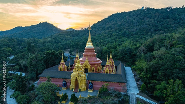 Obraz aerial view of the golden gate with intricate golden architecture at Phra Yai Wat Phra That Doi Phra Chan (Daibutsu) temple..A stunning view of a traditional temple surrounded by lush greenery