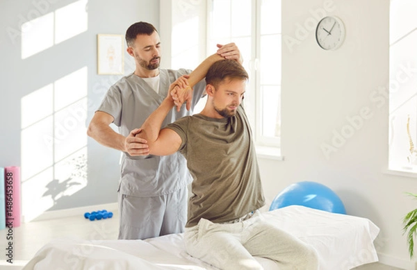 Fototapeta Therapist performing massage and stretching arm joints exercises to aid in the patient recovery. This physiotherapy and rehabilitation session improving joint mobility and promote medical healing.