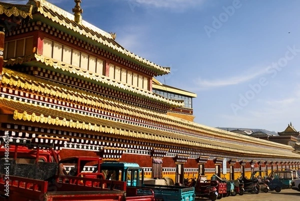 Fototapeta Colorful facade of Kirti Monastery (Gerdeng) in Ngawa, Amdo, Tibet, showcasing traditional Tibetan architecture and rows of vibrant prayer wheels lined along the outer wall.