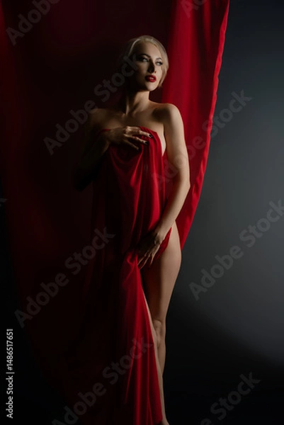 Fototapeta Elegant woman posing with red cloth in a studio setting