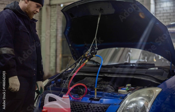 Fototapeta replacing antifreeze in a car, filling with coolant using a hose