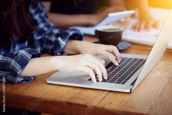 Fototapeta Teamwork,brainstorming concept.Young Asian creative managers team working with new startup project in modern office. Contemporary notebook on wood table.Horizontal, film effect
