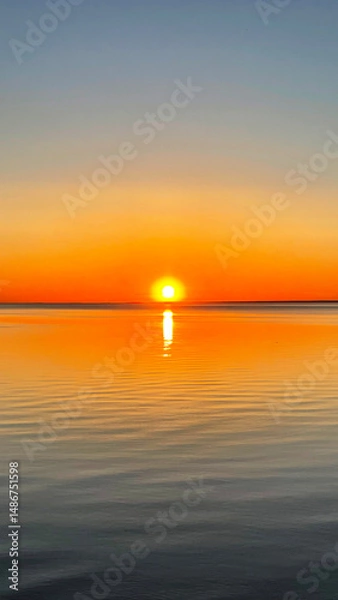 Fototapeta Beautiful sunset over the sea. The sun sets on the water. The sky is painted with bright colors. Summer evening. Sunset beach. Vertical photo.