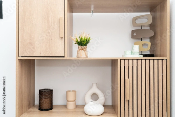 Obraz A stylish wooden shelf showcases minimalist decor including vases, a plant, and candle holders, emphasizing a clean, modern aesthetic in a well-lit space.