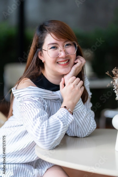 Obraz Portrait of beautiful happy Smiling asian woman relaxing sitting in cafe interior in coffee shop background