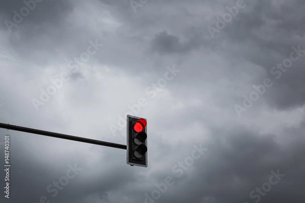 Fototapeta Red traffic light on a backdrop full of rain clouds