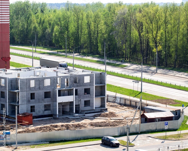 Fototapeta Construction of an apartment building against the backdrop of a forest in the city in summer, industry