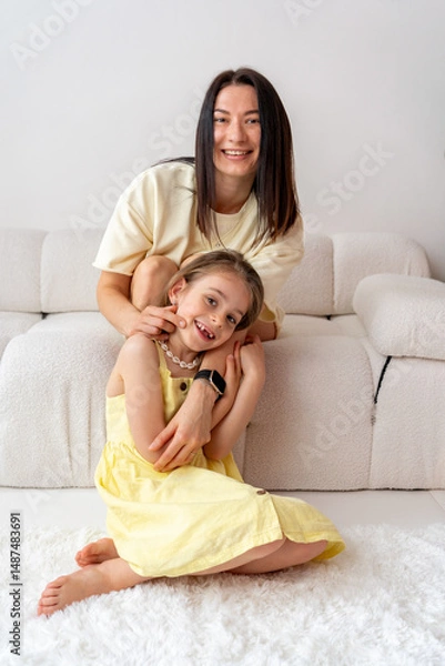 Fototapeta Smiling mother and daughter spending time together playing at home in white room. Family time. Mother's Day.