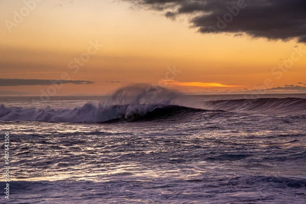Obraz The ocean is calm and the sky is orange. The waves are small and the water is dark blue