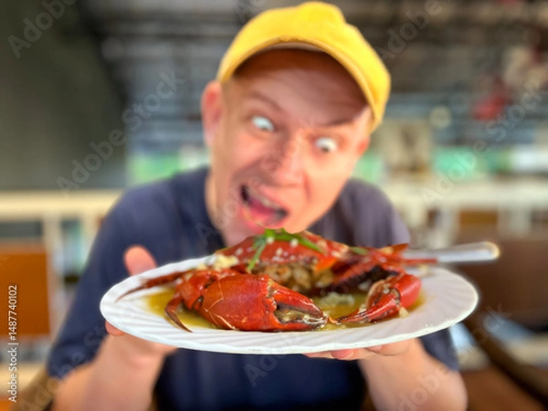 Fototapeta man eating crab, holding crab on plate and trying to bite