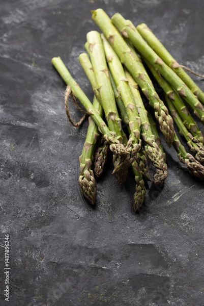 Fototapeta Bunch of fresh green asparagus on black surface