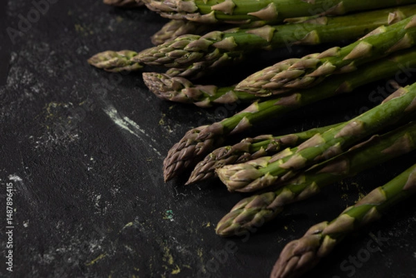 Fototapeta Bunch of fresh green asparagus on black surface