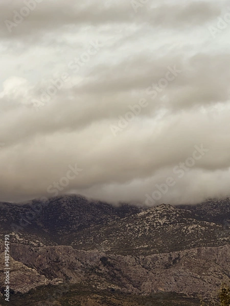 Fototapeta Low clouds covering the mountain peaks on a cloudy day