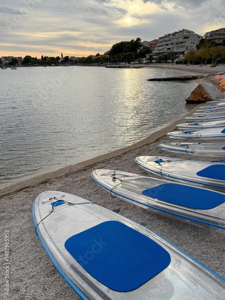 Fototapeta Transparent paddle boards resting on the beach at sunset in Croatia
