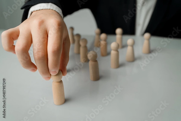Obraz Hand Picking Wooden Figure Among Group of Unfinished Figurines