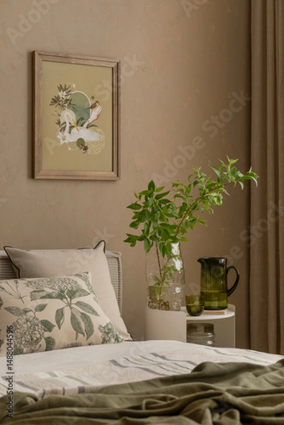 Obraz Close-up of a cozy bed corner with green glassware, leafy branches in a vase, and a botanical cushion under a nature-inspired mock up poster. Home decor.