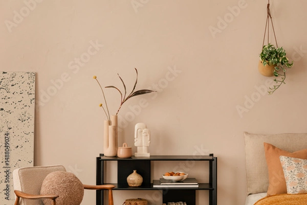 Obraz Minimalist composition of bedroom interior with bed, boucle armchair, round pouf, beige and orange bedding, plants, beige wall, vase with dried flowers and personal accessories. Home decor. Template.