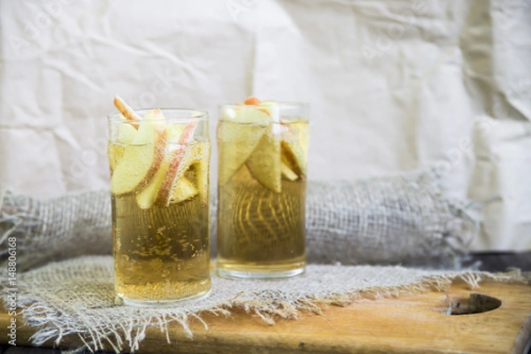 Fototapeta Apple cider with slices of apples in transparent glasses on a wooden board