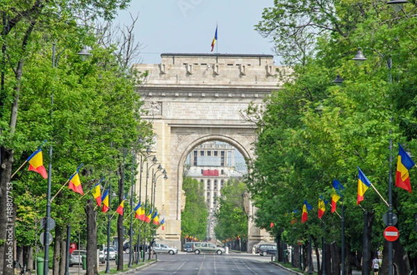 Fototapeta The Arch of Triumph (Arcul de Triumf) from Bucharest Romania, International Day with romanian flags, view from Kisseleff Avenue