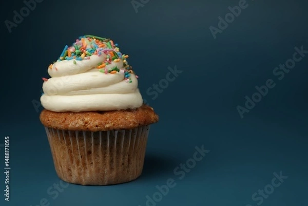 Fototapeta Sprinkled cupcake with creamy white frosting