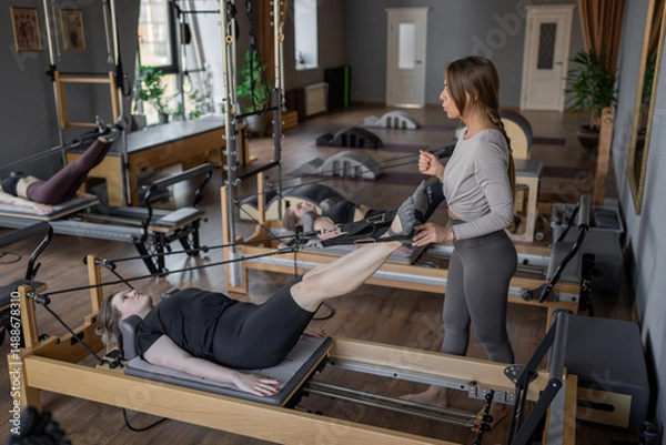 Fototapeta A detailed closeup of a foot work and core exercise on a Balanced Body Reformer machine illuminated by sunlight