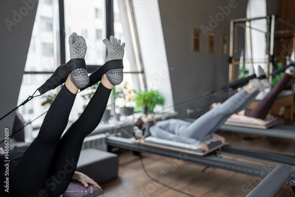 Fototapeta A detailed closeup of a foot work and core exercise on a Balanced Body Reformer machine illuminated by sunlight