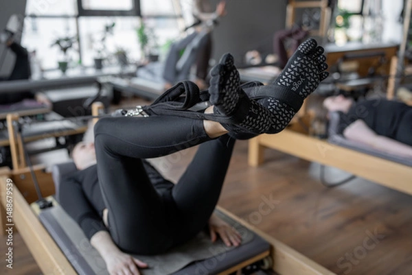 Fototapeta A detailed closeup of a foot work and core exercise on a Balanced Body Reformer machine illuminated by sunlight