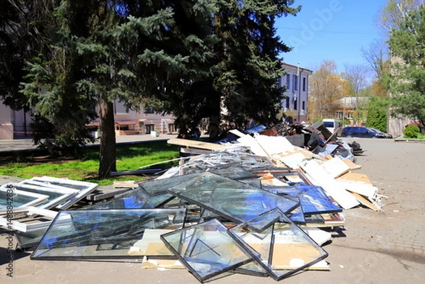 Obraz War in Ukraine. Broken windows piled up in destroyed house after Russian missile strike, Broken glass, debris of building